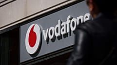 A Lady walks by a Vodafone shop with the company logo on display