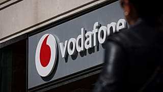 A Lady walks by a Vodafone shop with the company logo on display