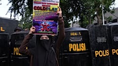 Eine Frau hält ein Plakat während einer Demonstration gegen die britische Band Coldplay vor ihrem Konzert in Jakarta, Indonesien