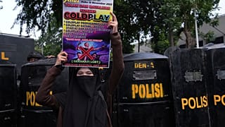 Eine Frau hält ein Plakat während einer Demonstration gegen die britische Band Coldplay vor ihrem Konzert in Jakarta, Indonesien