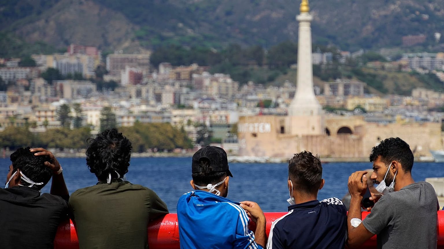 FILE: Migrants stand on the deck of the Spanish NGO Open Arms lifeguard ship as they wait to get off the ship after docking at Messina port, in Sicily on Sept. 22, 2022.