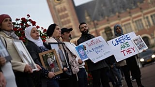 تجمع افراد به همراه تصویر مفقودشدگان، بیرون از دادگاه لاهه در جلسه رسیدگی به اتهامات اعمال شکنجه توسط دولت سوریه به تاریخ دهم اکتبر ۲۰۲۳