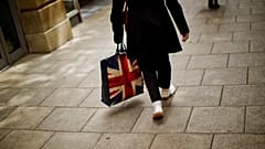In this Tuesday, July 5, 2016 photo, a woman carrying a bag decorated with a Great Britain's union flag, walks a long a street in downtown Peterborough, East of England.