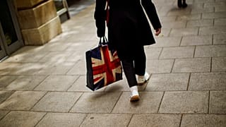 In this Tuesday, July 5, 2016 photo, a woman carrying a bag decorated with a Great Britain's union flag, walks a long a street in downtown Peterborough, East of England.
