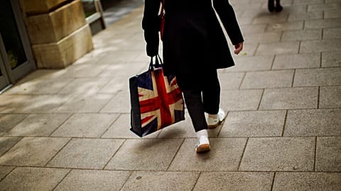 In this Tuesday, July 5, 2016 photo, a woman carrying a bag decorated with a Great Britain's union flag, walks a long a street in downtown Peterborough, East of England.