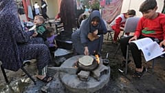 أم فلسطينية لاجئة تعد الخبز في رفح