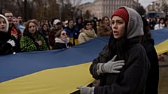 A woman sings the Ukraine national anthem during a demonstration in Kyiv on Saturday, as people gathered to demand the reallocation of public funds to the Armed Forces