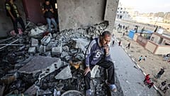 A Palestinian man cries, looks at the destruction after Israeli fighter jets strike residential buildings in Hamad Town, northwest of Khan Yunis, Gaza