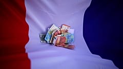 Bank notes lie on a French flag, April 7, 2022. 