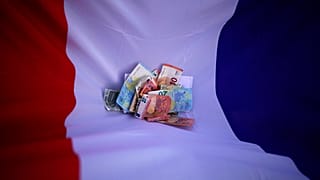 Bank notes lie on a French flag, April 7, 2022.