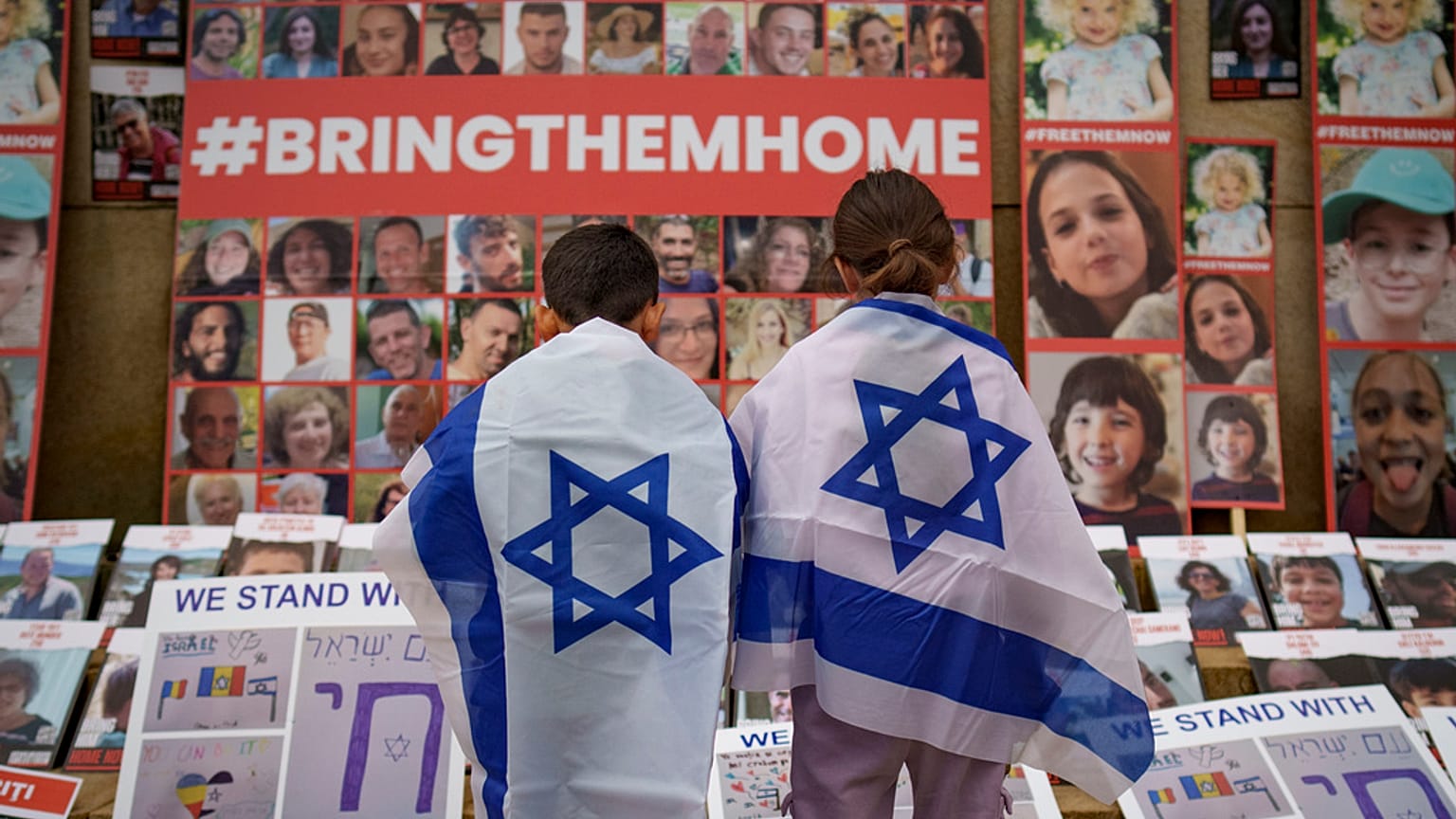 FILE - Children look at photographs of Israelis kidnapped by Hamas during a rally joined by hundreds in solidarity with Israel in Romania, 2023. 