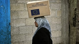 Une femme palestinienne porte une boîte contenant des fournitures données par l'Union européenne dans un entrepôt du camp de réfugiés de Jebaliya, dans le nord de la bande de Gaza.