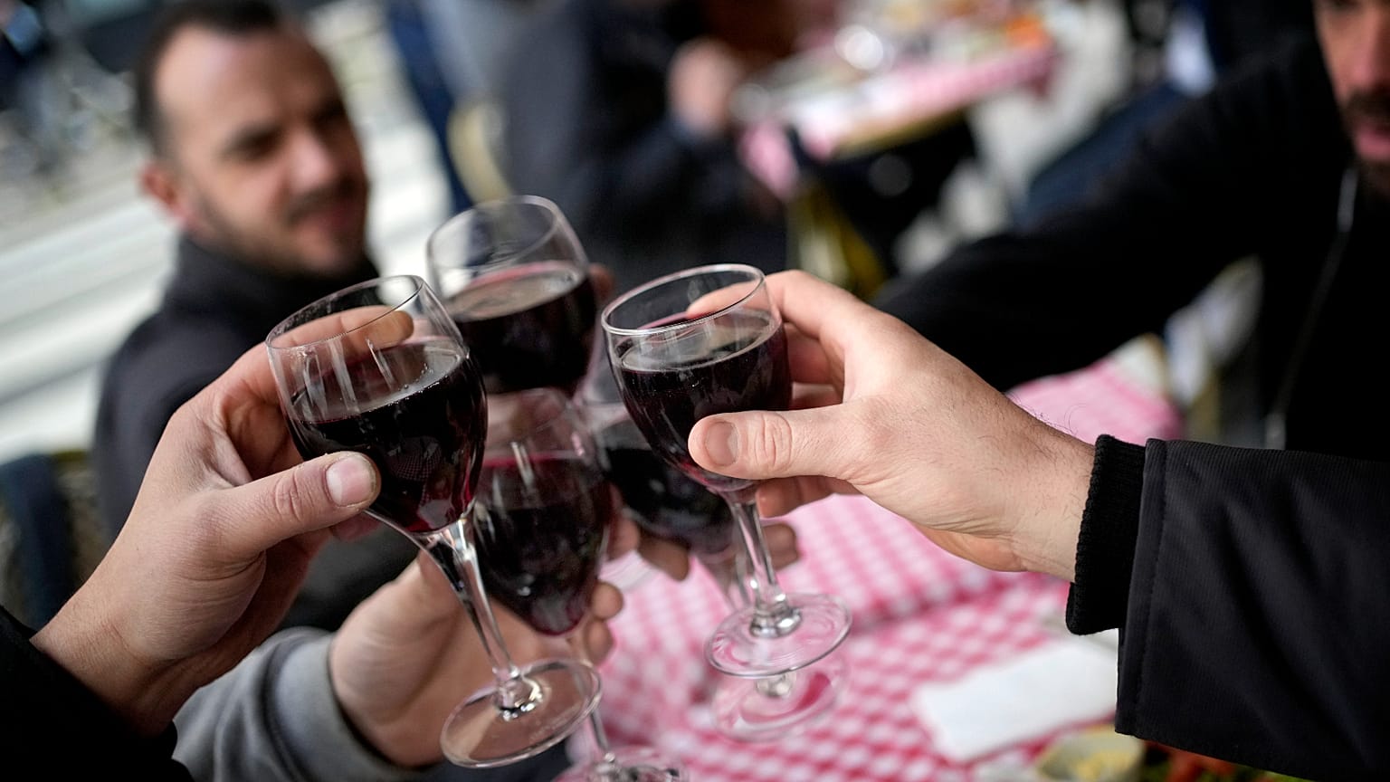 Customers toast with glasses of red wine in a restaurant outside Paris, France.