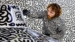 British artist Sam Cox, better known as Mr. Doodle, draws on a model spaceship for a live art performance at Central MTR Station in Hong Kong on November 19, 2023. 