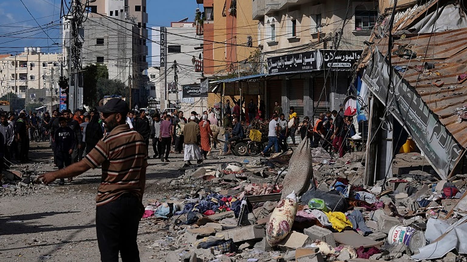Palestinos junto a un edificio atacado por Israel en el campo de refugiados de Nusseirat, en el centro de la Franja de Gaza, el martes 21 de noviembre