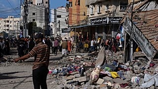 Palestinos junto a un edificio atacado por Israel en el campo de refugiados de Nusseirat, en el centro de la Franja de Gaza, el martes 21 de noviembre