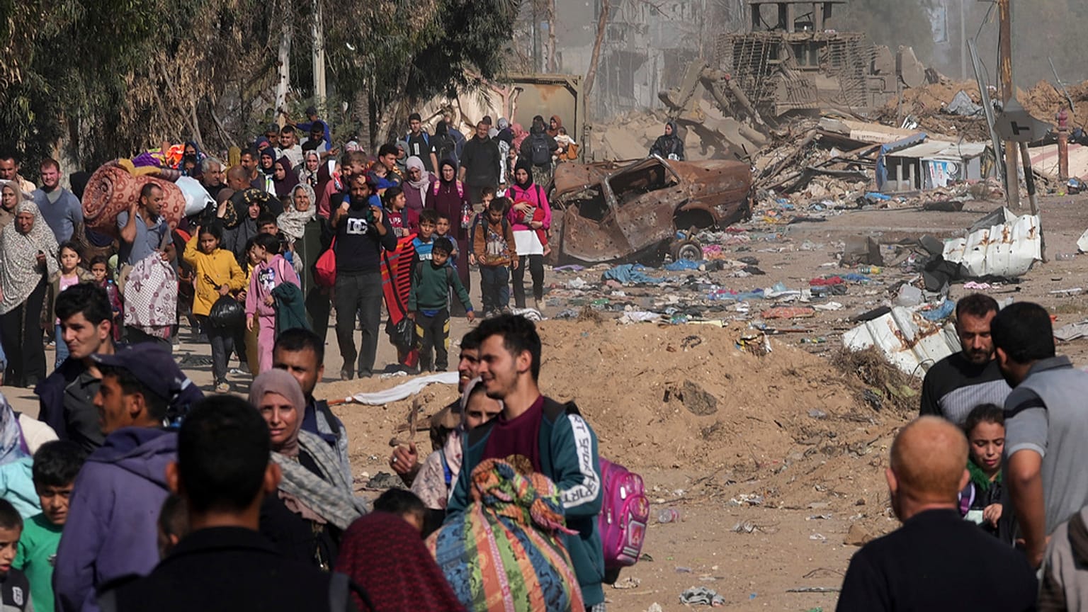 فلسطينيون يفرون إلى جنوب قطاع غزة على طول شارع صلاح الدين، على مشارف مدينة غزة، أمام جرافة تابعة للجيش الإسرائيلي،18 نوفمبر، 2023.