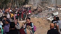 فلسطينيون يفرون إلى جنوب قطاع غزة على طول شارع صلاح الدين، على مشارف مدينة غزة، أمام جرافة تابعة للجيش الإسرائيلي،18 نوفمبر، 2023.