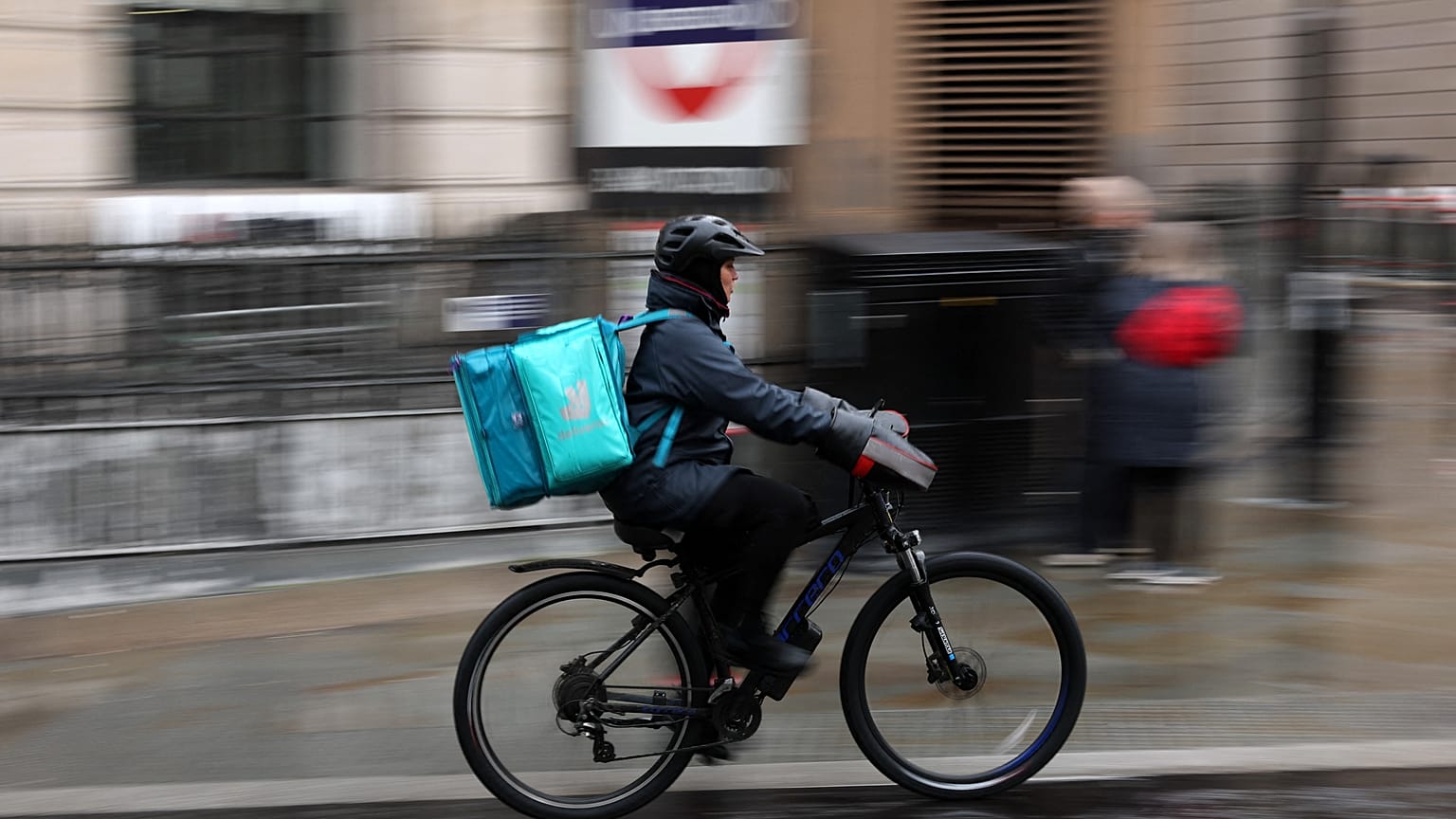 A Deliveroo rider cycling down the road
