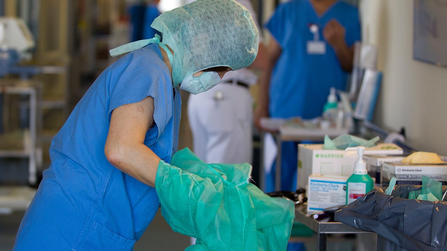 A nurse changes her protective clothing after treating an E. coli patient in Germany.