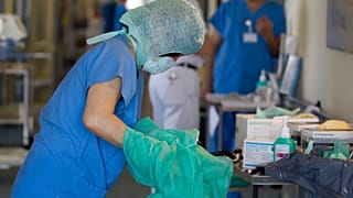 A nurse changes her protective clothing after treating an E. coli patient in Germany.