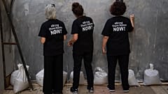 People write on an installation simulating a tunnel in Gaza in an act of solidarity with hostages believed to be held underground by Hamas and calling for their return, in Tel