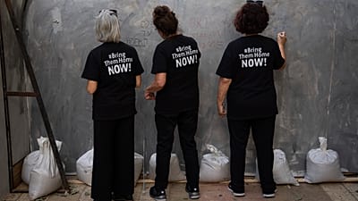 People write on an installation simulating a tunnel in Gaza in an act of solidarity with hostages believed to be held underground by Hamas and calling for their return, in Tel