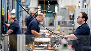Employees work in the battery assembly hall at a BMW factory.