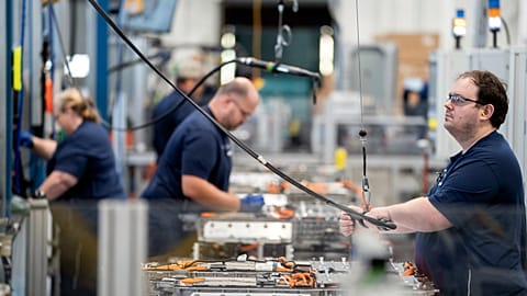 Employees work in the battery assembly hall at a BMW factory.