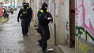 Agentes da polícia dirigem-se para a entrada de um edifício durante uma rusga em Berlim, Alemanha.