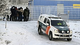 Migrants and a vehicle of the Finnish Border Guard are seen at the international border crossing at Salla, northern Finland, on November 22, 2023.