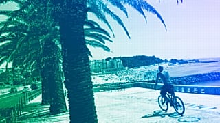 A man rides a bicycle by the beach in Oeiras, just outside Lisbon, July 2023