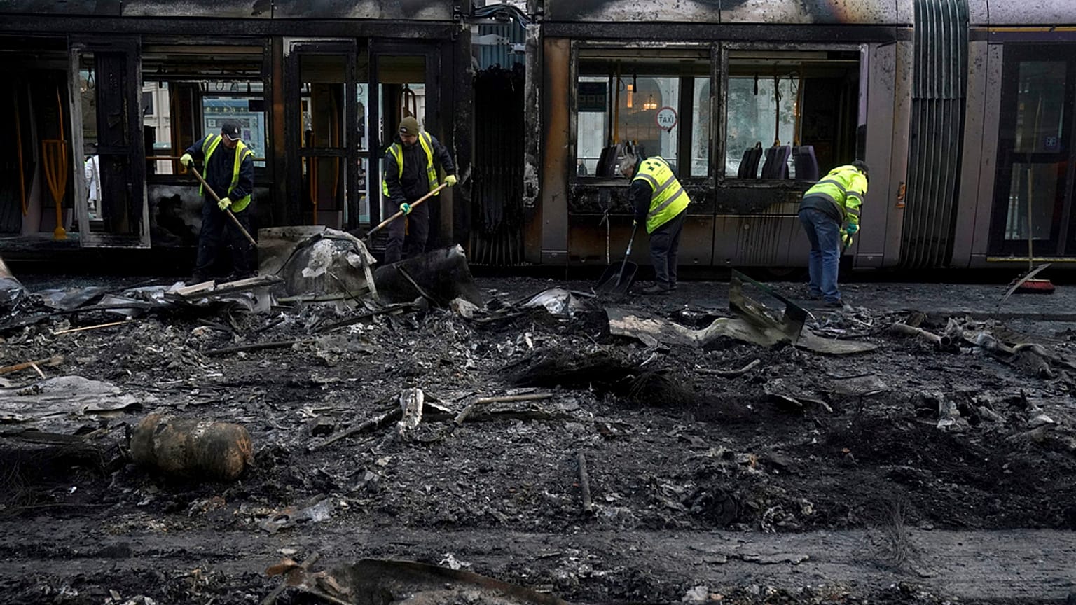 Destroços de um tram e um autocarro queimados são retirados da rua esta sexta-feira, no rescaldo da violência em Dublin na noite de quinta-feira.