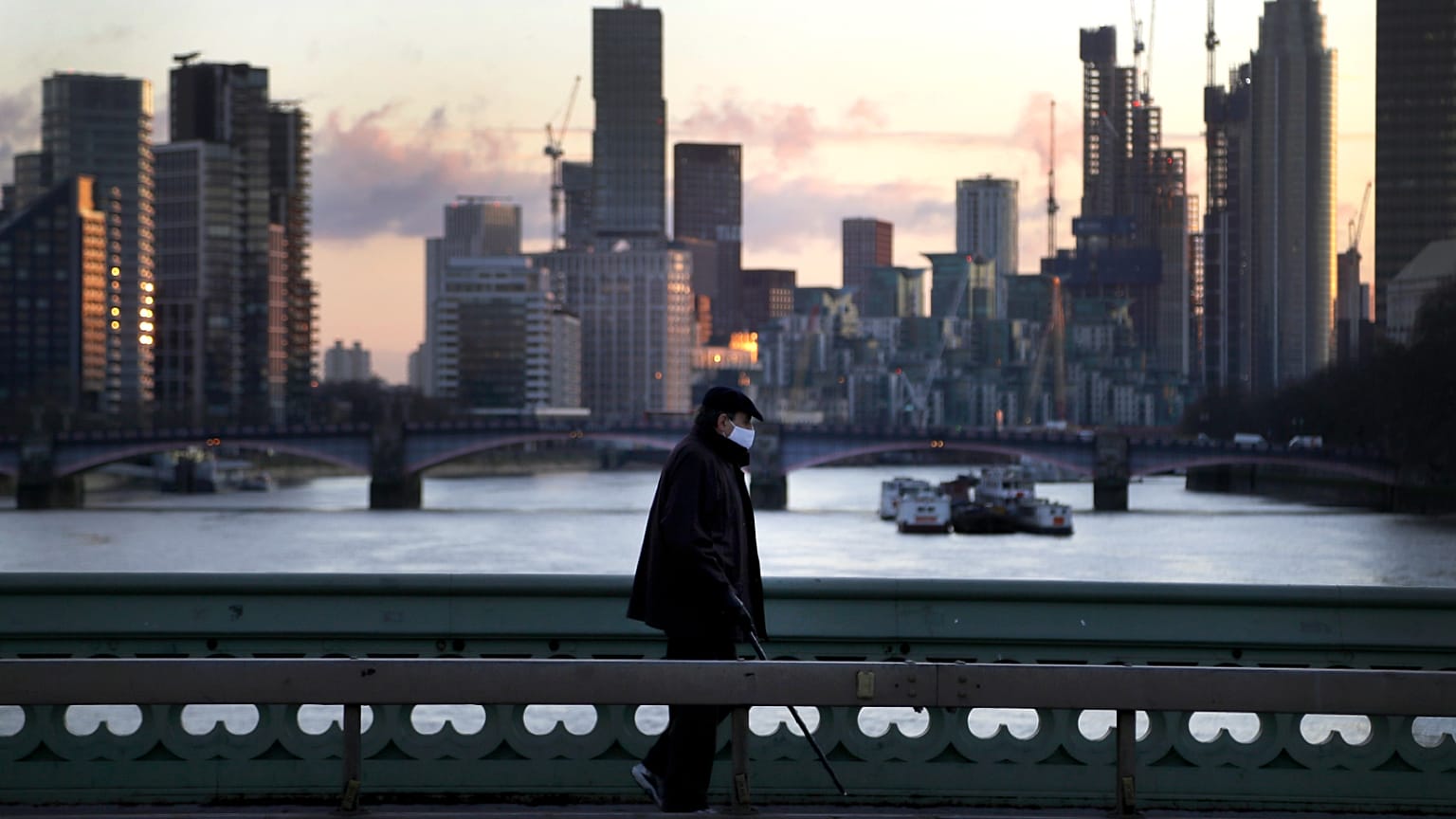 A man walks over Westminster Bridge as the sun sets in London, January 6, 2021