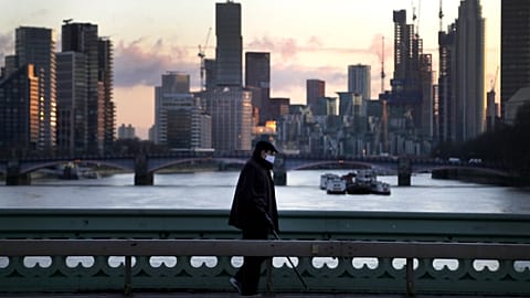 A man walks over Westminster Bridge as the sun sets in London, January 6, 2021