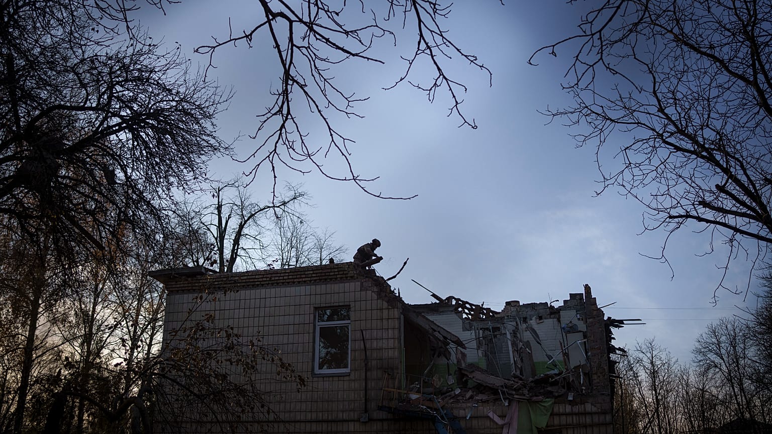 Un militaire ukrainien se tient au-dessus d'un jardin d'enfants endommagé à la suite d'une attaque de drone russe à Kiev, en Ukraine, le samedi 25 novembre 2023.