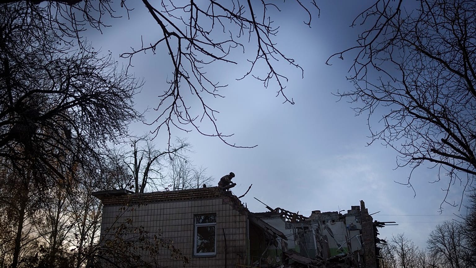 A Ukrainian serviceman stands atop a damaged kindergarten following a Russian drone attack in Kyiv, Ukraine, Saturday, Nov. 25, 2023.