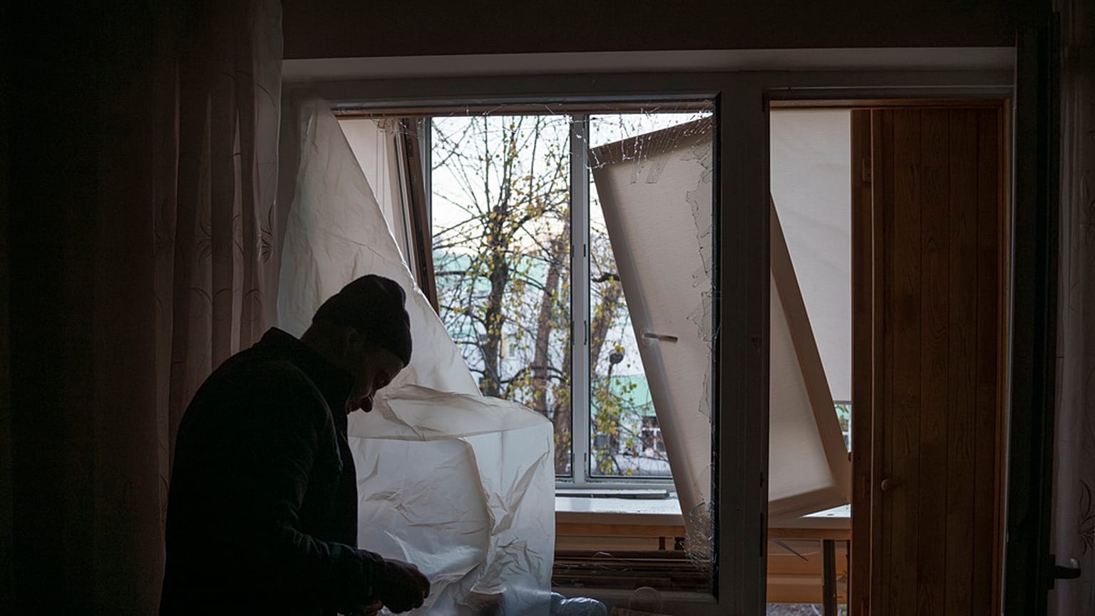Un hombre cubre las ventanas de su casa tras el ataque a Kiev.