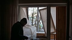 Un hombre cubre las ventanas de su casa tras el ataque a Kiev.