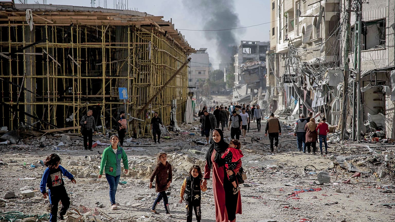 سيدة فلسطينية تسير وسط الدمار والحطام مع أطفالها في شمال غزة خلال فترة الهدنة بين إسرائيل وحماس