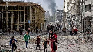 سيدة فلسطينية تسير وسط الدمار والحطام مع أطفالها في شمال غزة خلال فترة الهدنة بين إسرائيل وحماس