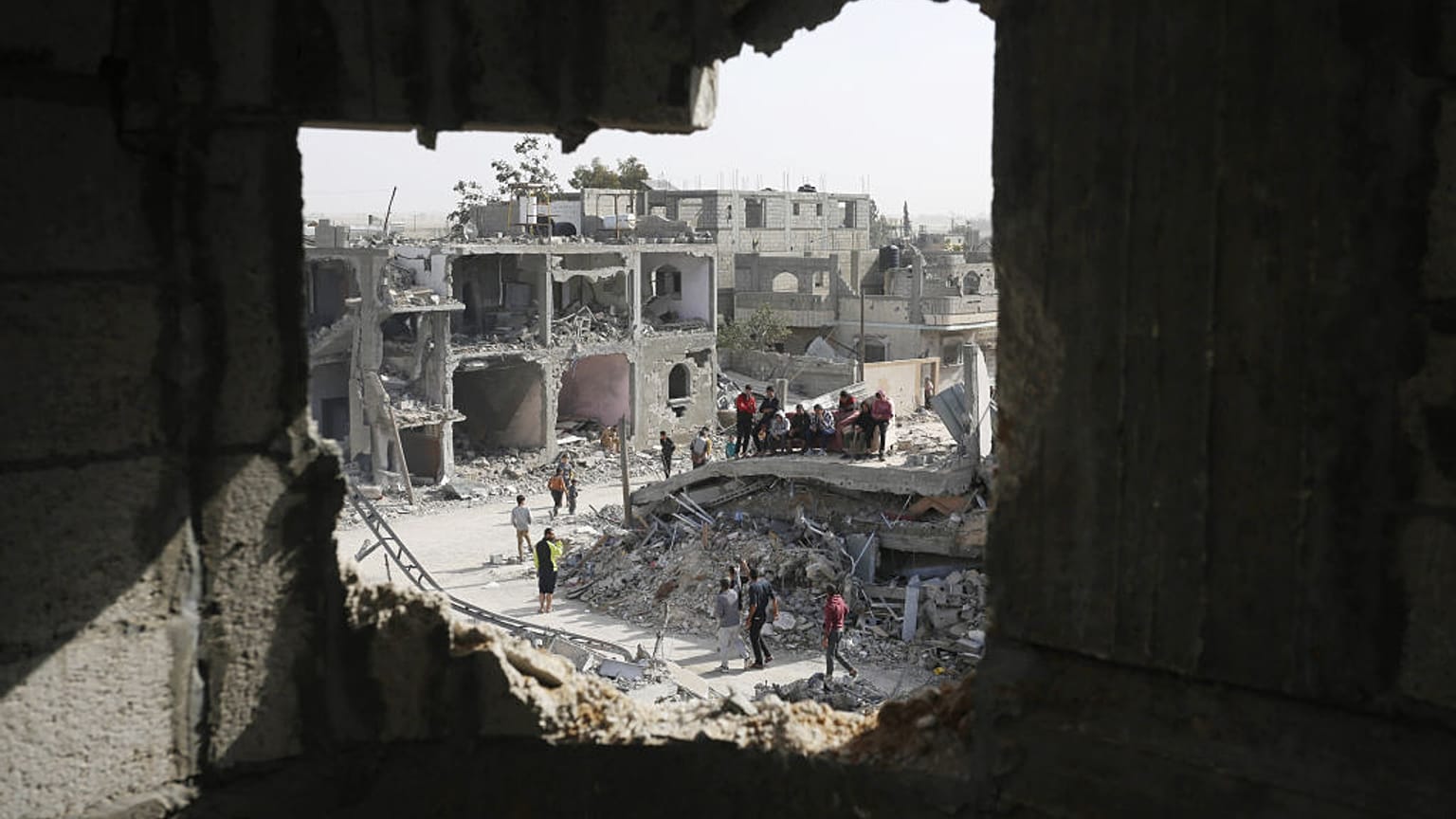 Palestinians sit on a couch amid wreckage of the residential areas after Israeli attacks during third day of the humanitarian pause in Khan Yunis, Gaza