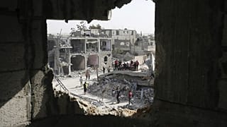 Palestinians sit on a couch amid wreckage of the residential areas after Israeli attacks during third day of the humanitarian pause in Khan Yunis, Gaza