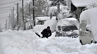 Un hombre quita la nieve con una pala, al lado de su coche, en la ciudad de Isperih, en el nordeste de Bulgaria, el domingo 26 de noviembre de 2023.