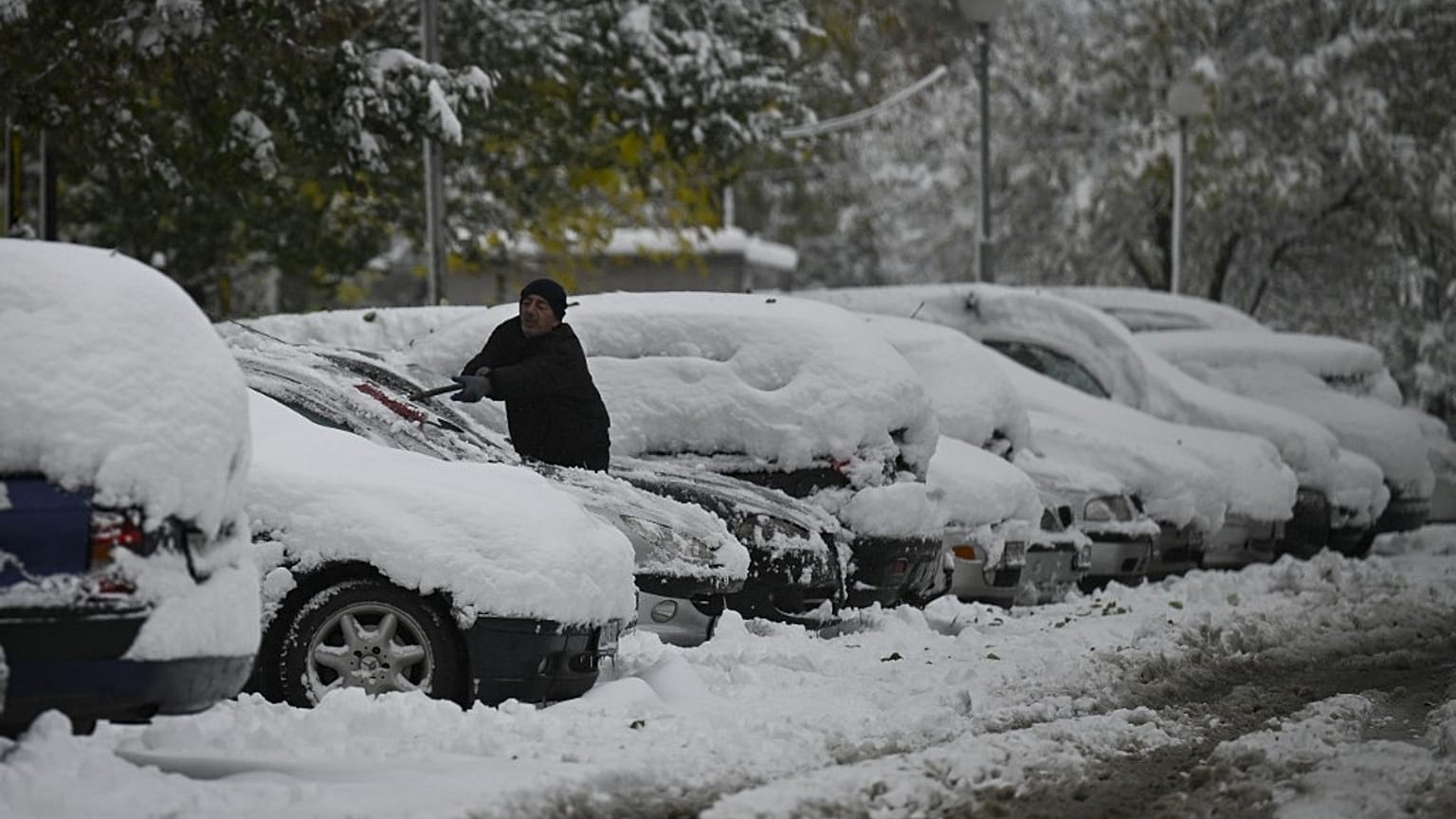 Anwohner in einem Vorort von Sofia kratzt Schnee von seinem Auto