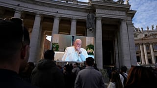 A giant screen broadcasts Pope Francis coughing during the Angelus noon prayer, from the chapel of the hotel at the Vatican grounds where he lives, Sunday, Nov. 26, 2023.