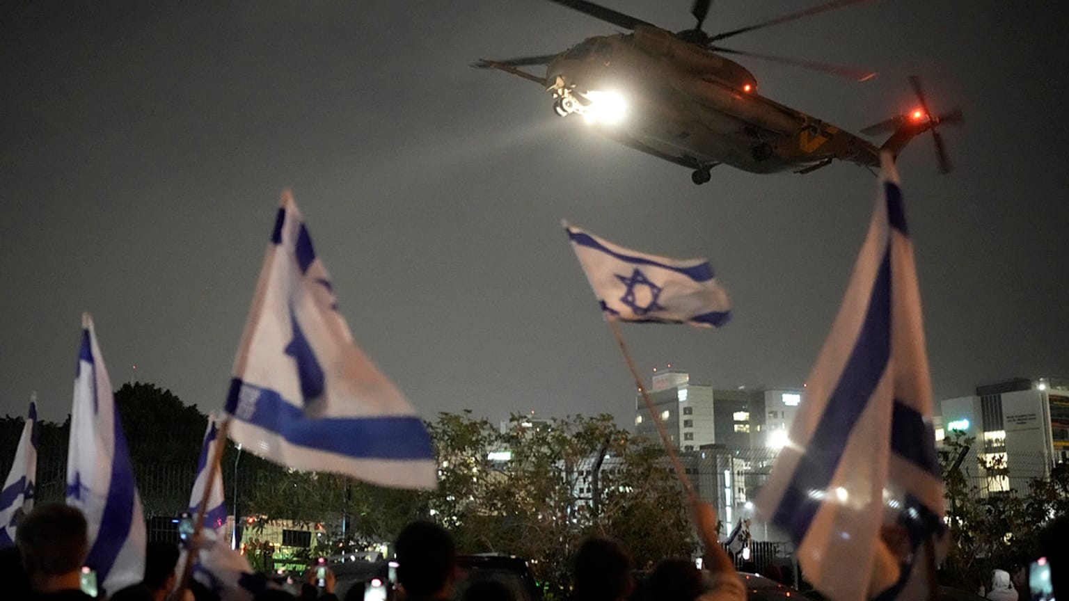 Menschen schwenken israelische Flaggen, als ein Hubschrauber mit von der Hamas freigelassenen Geiseln in Israel landet. 