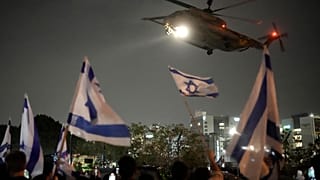 Menschen schwenken israelische Flaggen, als ein Hubschrauber mit von der Hamas freigelassenen Geiseln in Israel landet. 