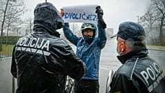 Ein Demonstrant in Ljubljana mit einem Plakat mit der Aufschrift "Heuchler" stellt sich während der Gedenkfeier für die Opfer von COVID-19 den Polizisten entgegen.