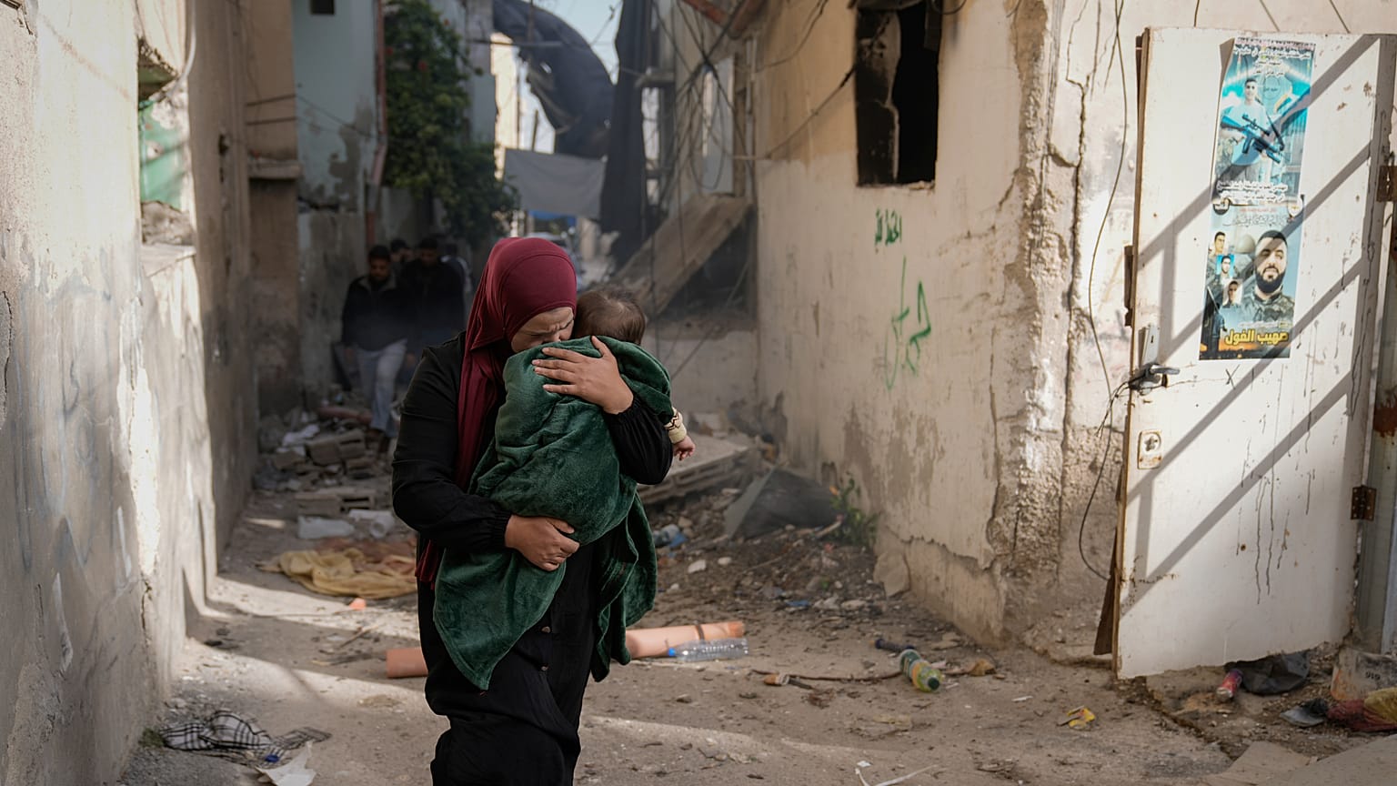 امرأة فلسطينية تحمل طفلًا وتهرب في أحد شوارع مخيم جنين بعد اجتياحه من قبل الجيش الإسرائيلي
